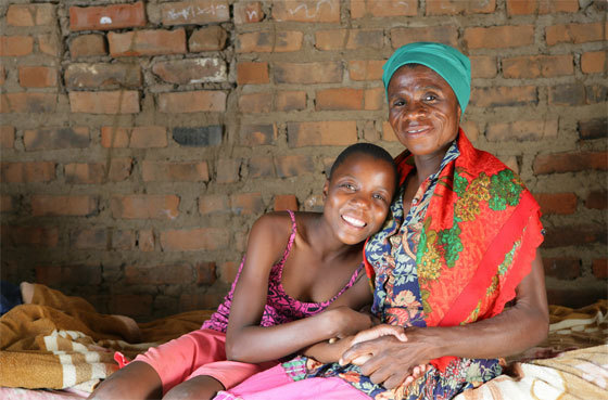 Monica, séropositive, et sa petite-fille Sympathy Tshuma, 14 ans, sont assises chez elles sur un lit, dans le village de Makuzeze à environ 200 kilomètres au sud de Bulawayo, la deuxième plus grande ville du Zimbabwe. L’aide aux adolescents sur les questions de prévention et de traitement est très importante. (UNICEF/G. Pirozzi)